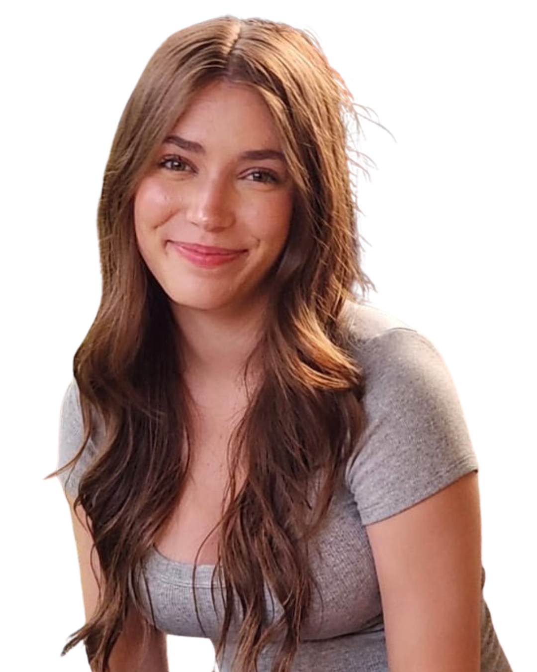 A smiling young woman with long wavy brown hair wearing a gray t-shirt against a white background.