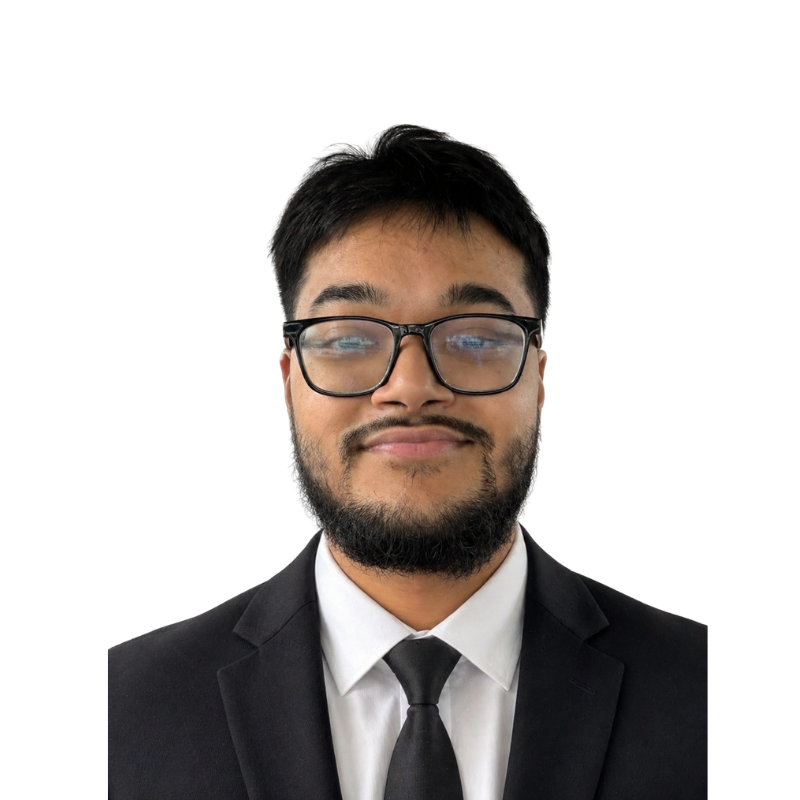 A man with glasses, a beard, and a mustache wearing a black suit, white shirt, and black tie, smiling, against a white background.