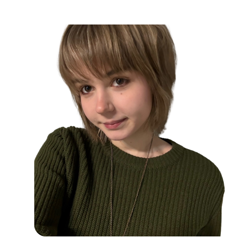 A young person with short, light brown hair wearing a dark green knitted sweater and a thin chain necklace, smiling slightly, against a plain white background.