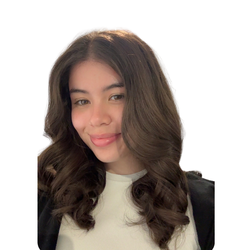 Young woman with long, wavy brown hair, winking, smiling, wearing a light-colored top and black jacket, against a white background.