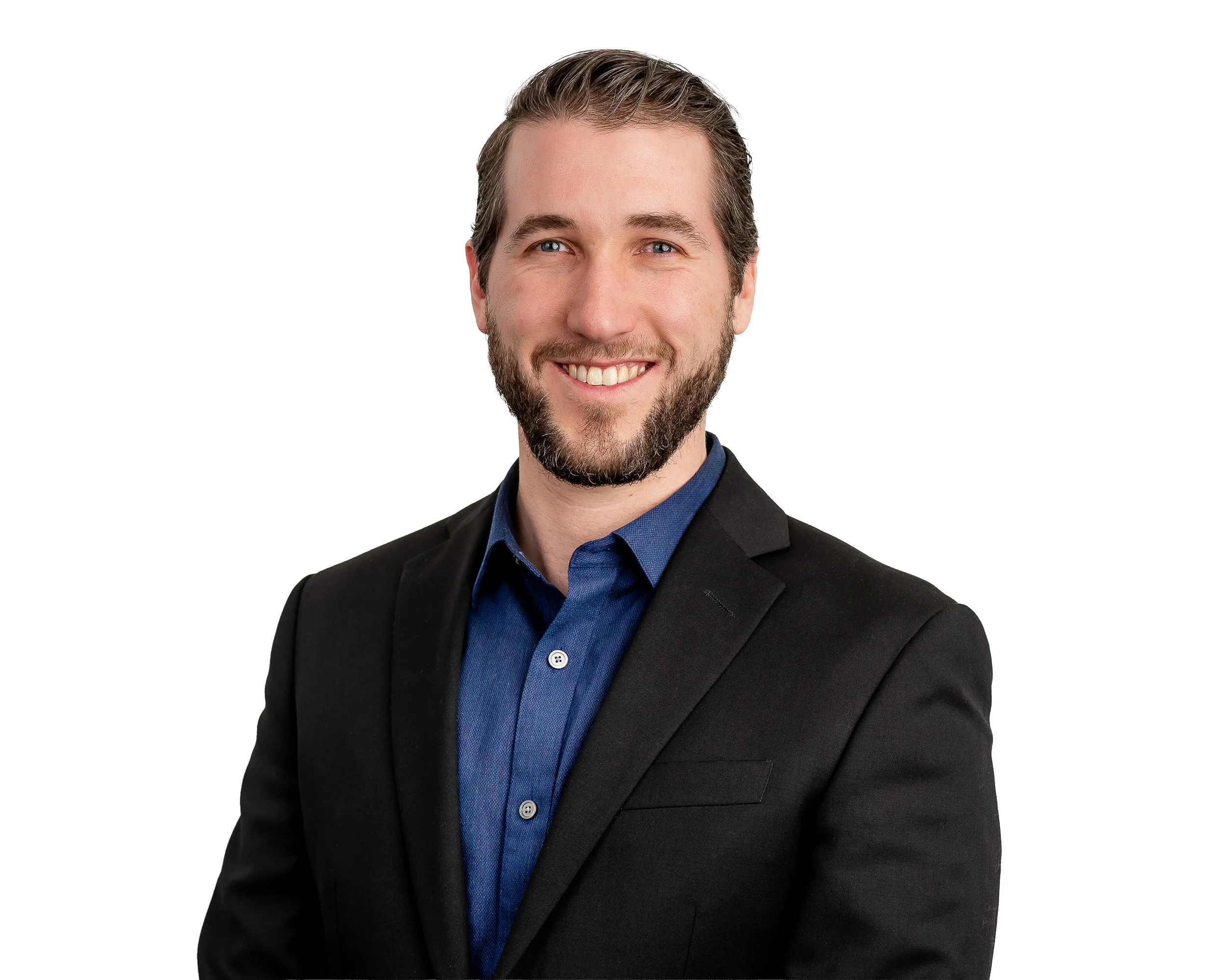 A smiling man with brown hair, blue eyes, and a beard, wearing a black suit jacket and blue shirt, against a plain white background.