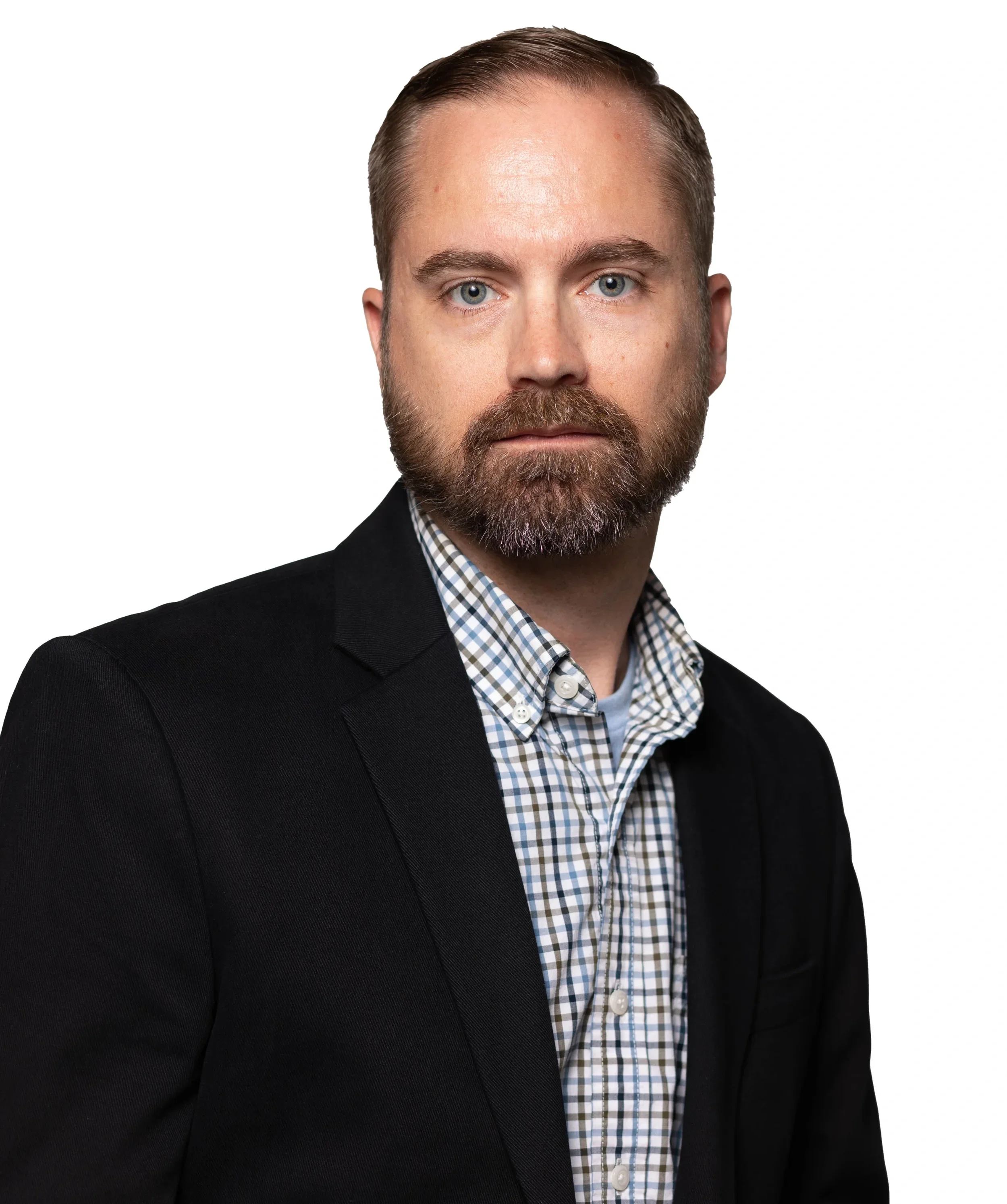 Close-up of a man with short brown hair and a beard, wearing a black blazer and a checked collared shirt, against a plain white background.