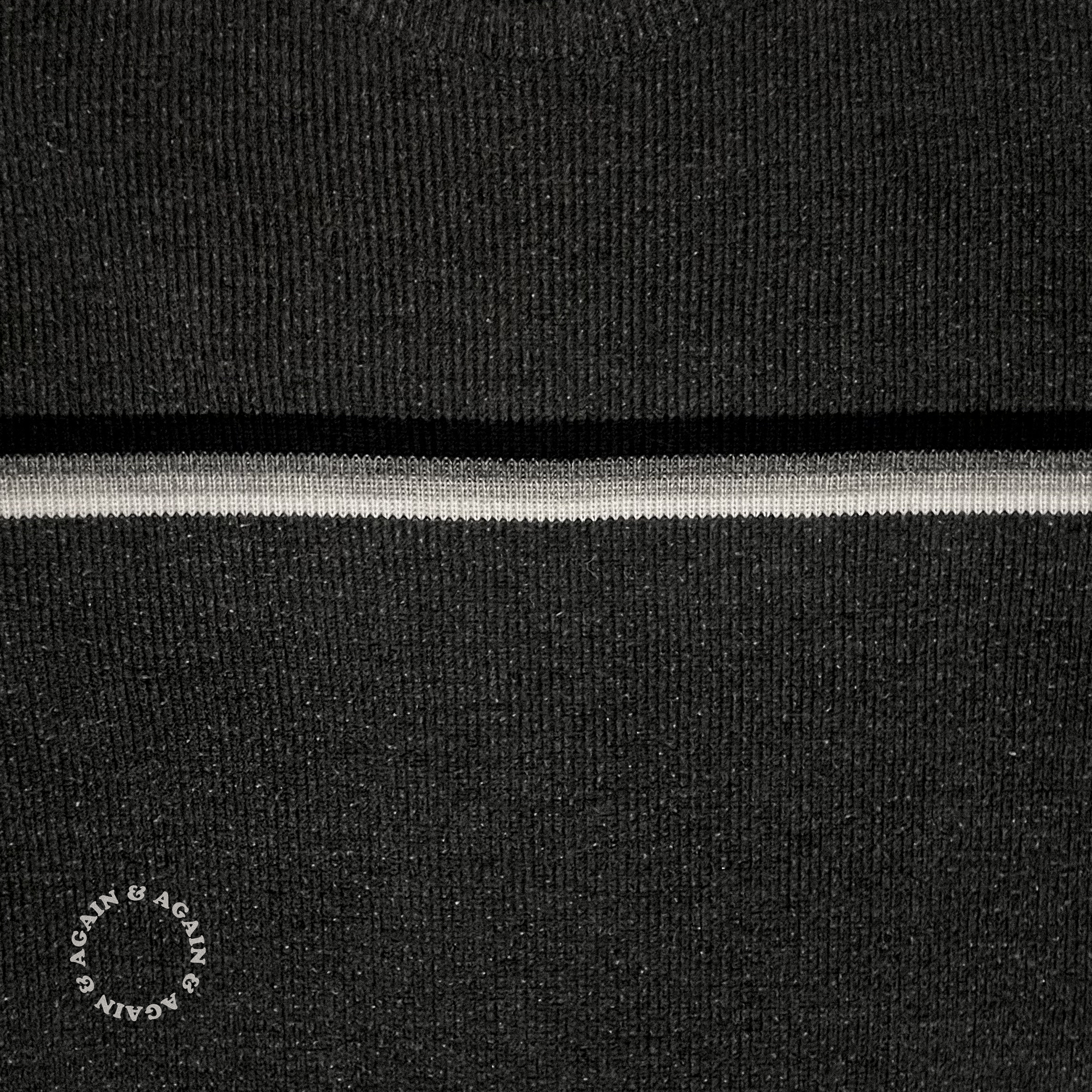 Close-up of black sweater with a three black, gray, and white stripes running horizontally. In the bottom left corner is circular text that reads "Again & Again & Again" with an extra "&" at the end, creating an infinite loop.