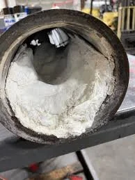 Close-up of a large, round pipe with white powdery substance inside, likely in an industrial setting.
