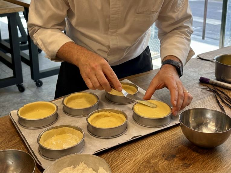 Person preparing small pie crusts with filling in a baking dish.