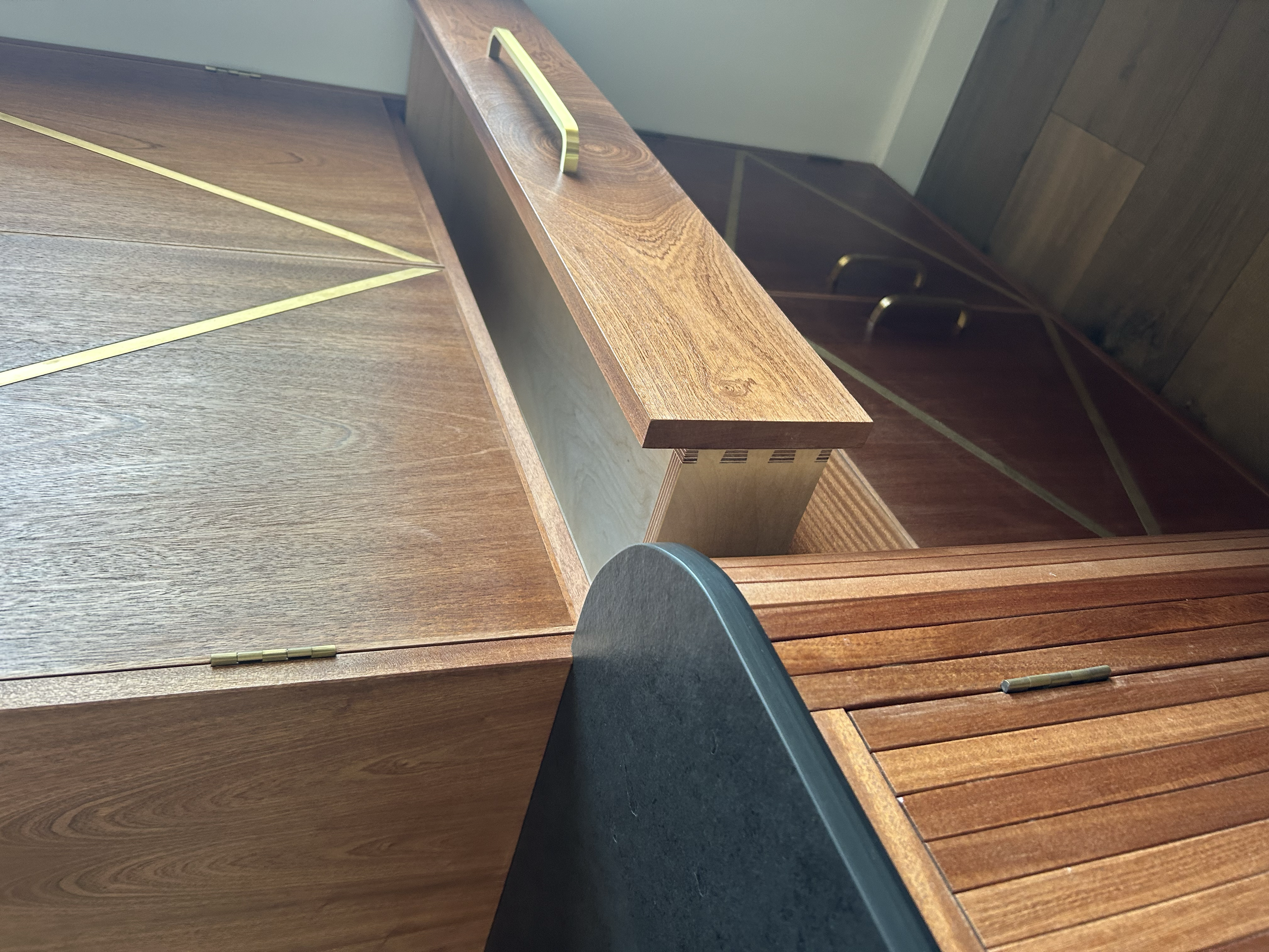 Close-up of a mid-century modern wooden credenza with open drawers, brass handles, and a black round tabletop.