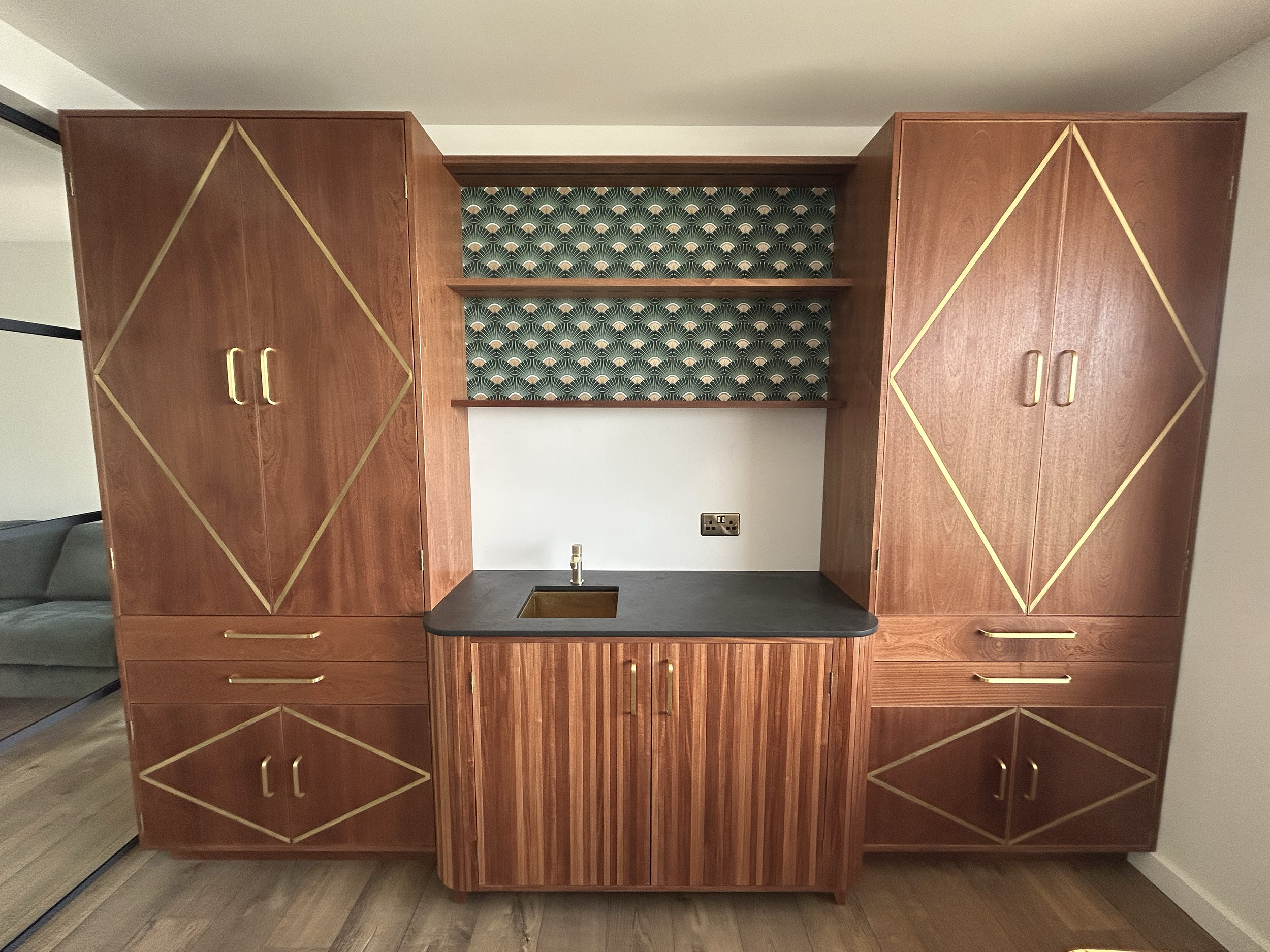 Art Deco-style wooden Bar with brass geometric trim, patterned backsplash, open shelves, sink, and dark countertop