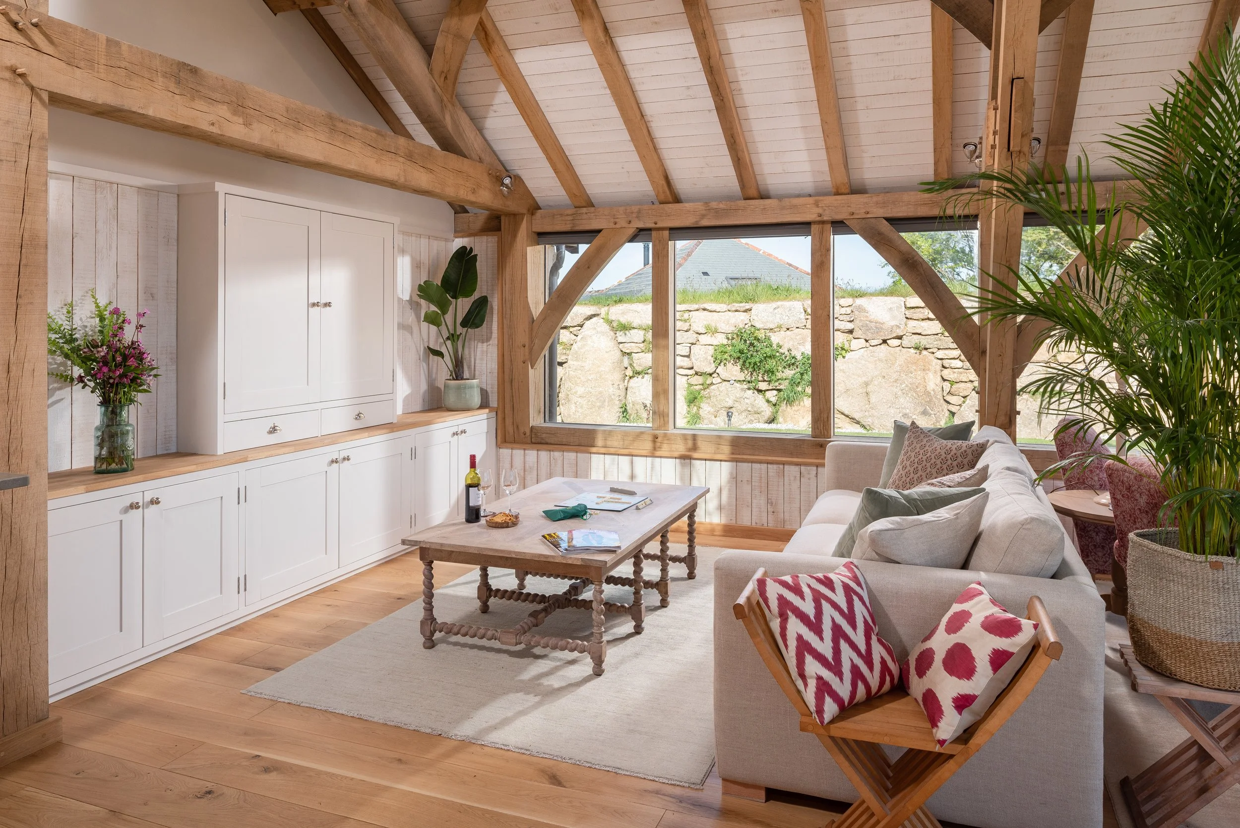 Bright rustic living room with exposed timber beams, white built-in cabinets.