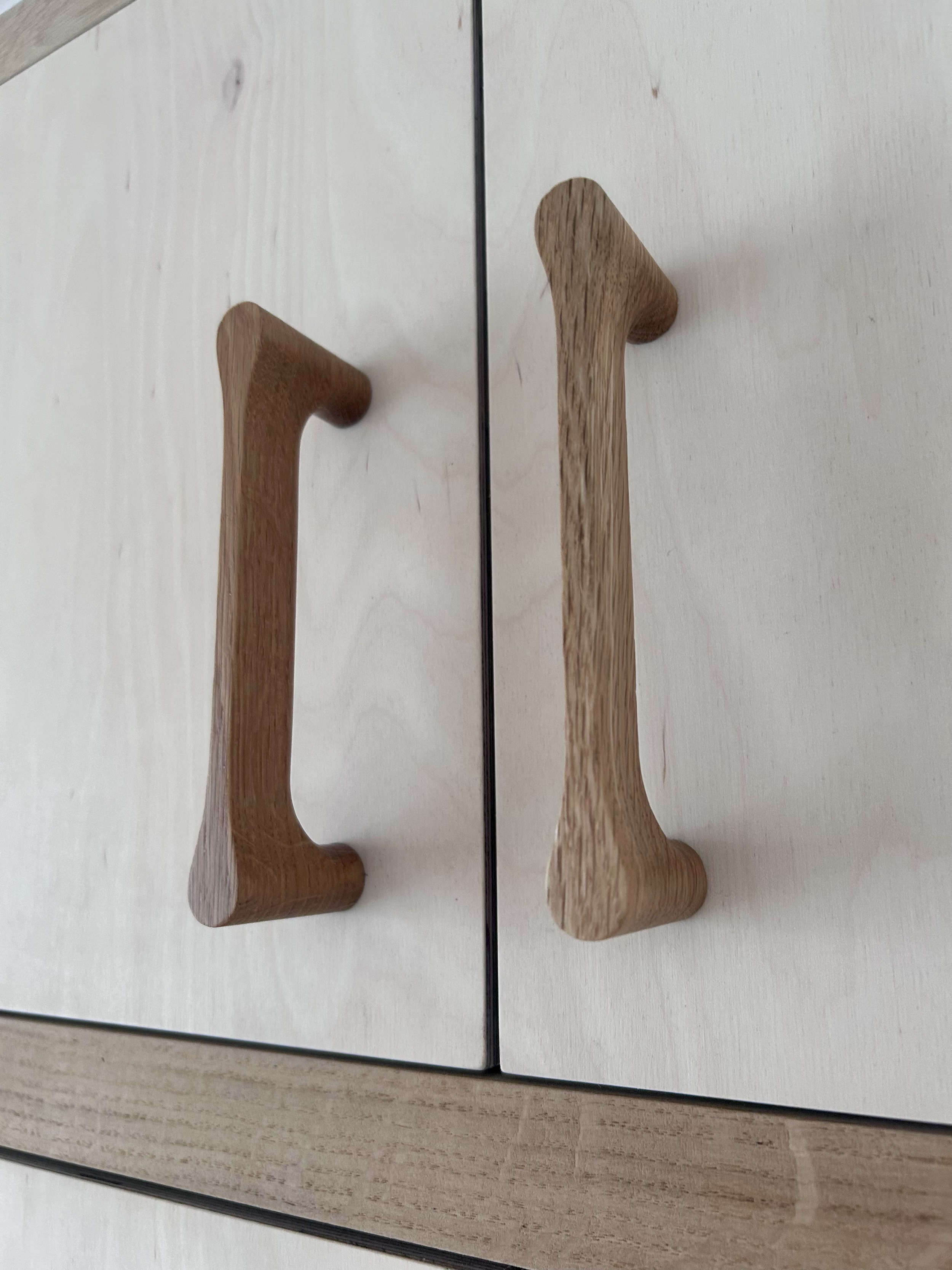 Close-up of a handcrafted wooden coat hook mounted on a light birch ply doors
