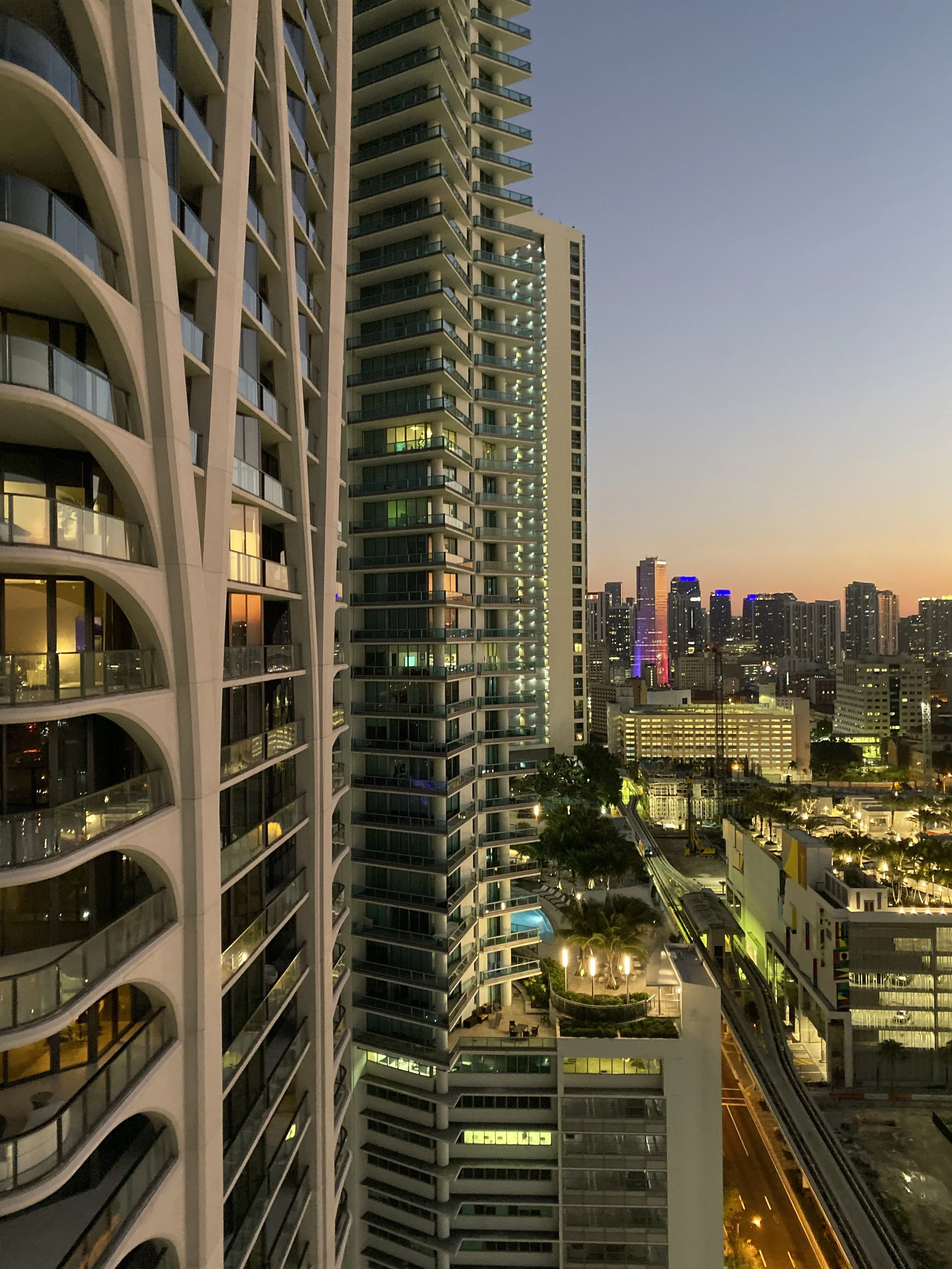 Nighttime cityscape view of high-rise buildings with lit windows and a clear sky, showing the downtown area with various skyscrapers in the background.