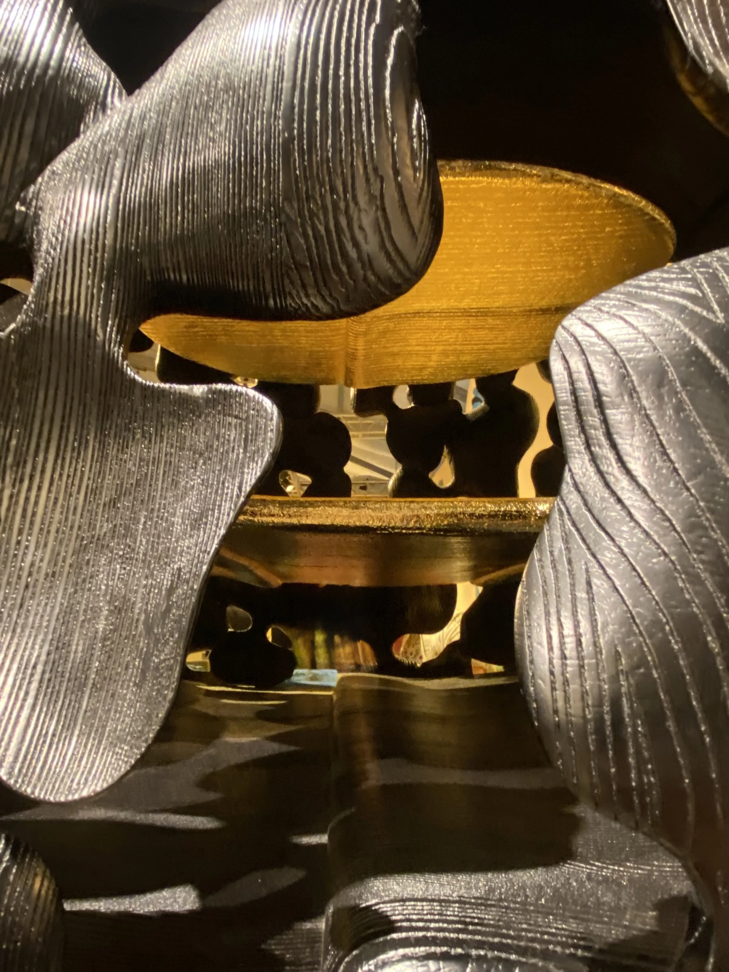 Close-up view of a decorative arrangement of multiple metallic and gold-colored objects, with textured surfaces reflecting light.