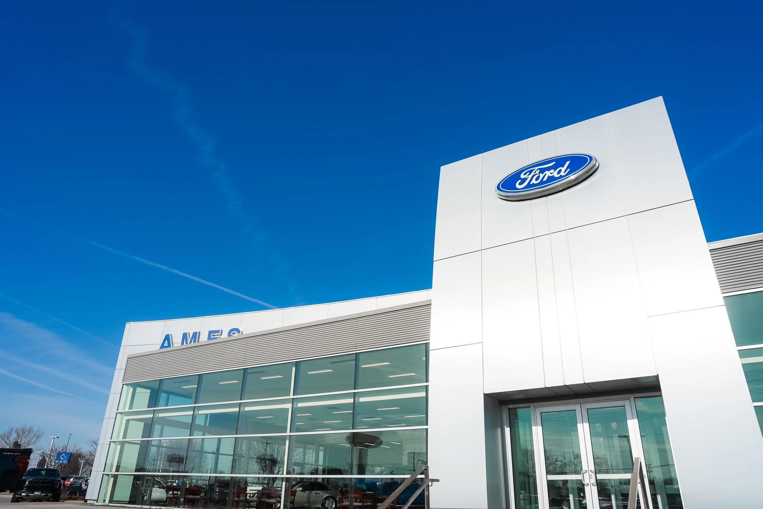 Exterior view of a Ford dealership building with large glass windows and the Ford logo prominently displayed.