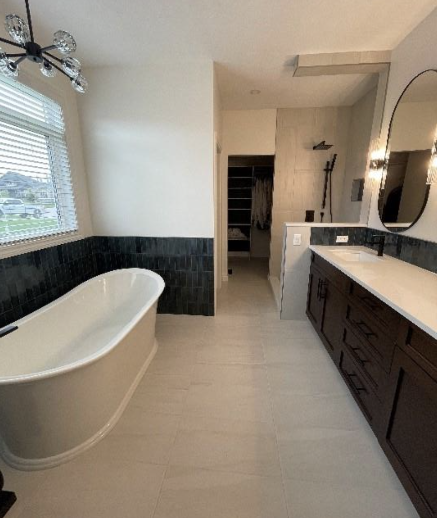 Modern bathroom with a freestanding bathtub, dark wood vanity with white countertop, large mirror, black fixtures, window with blinds, and an open walk-in closet in the background.