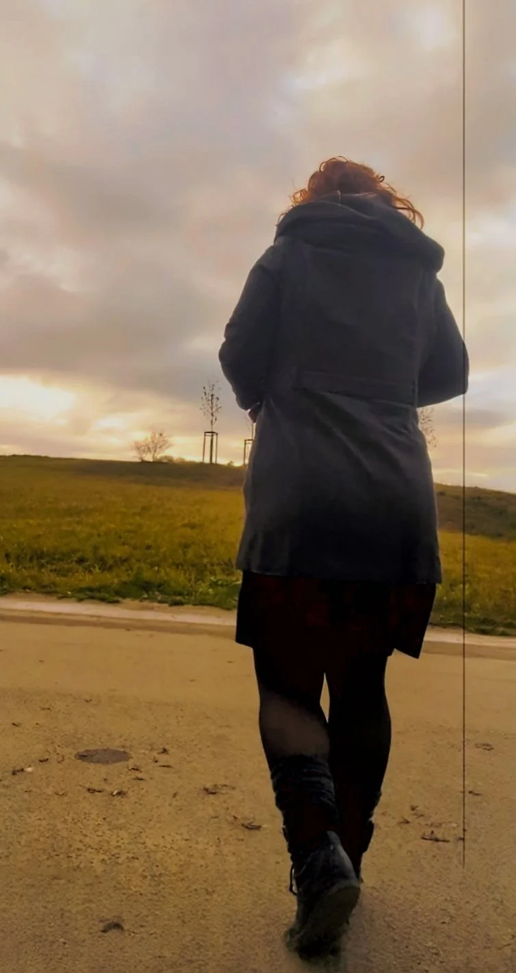 Eine Person in dunkler Jacke läuft auf einem Weg im Freien bei bewölktem Himmel.