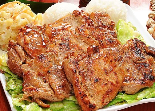 Grilled pork chops served with mashed potatoes, macaroni and cheese, and green lettuce