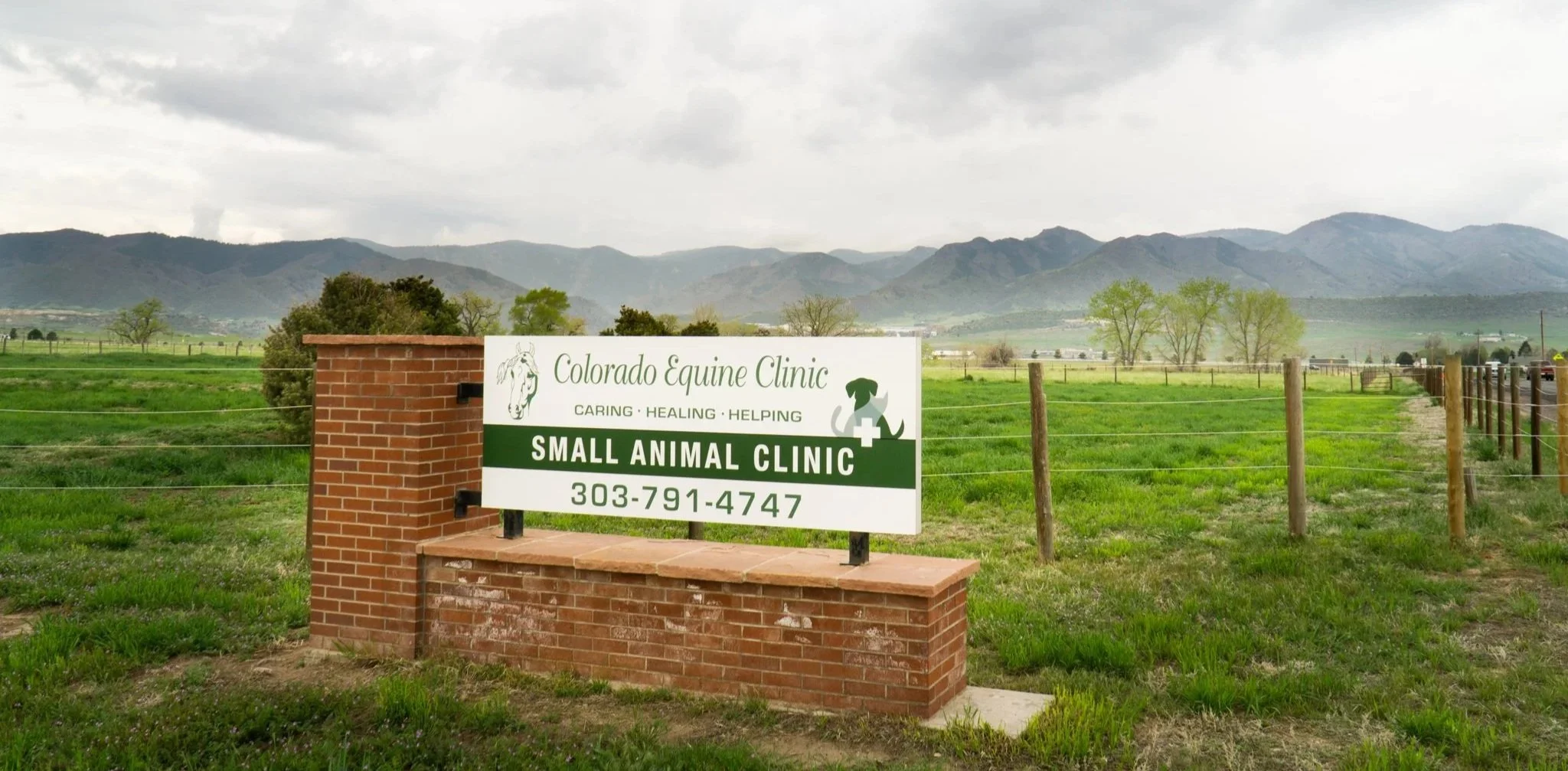 Sign for Colorado Equine Clinic and Small Animal Clinic with green fields and mountains in the background.