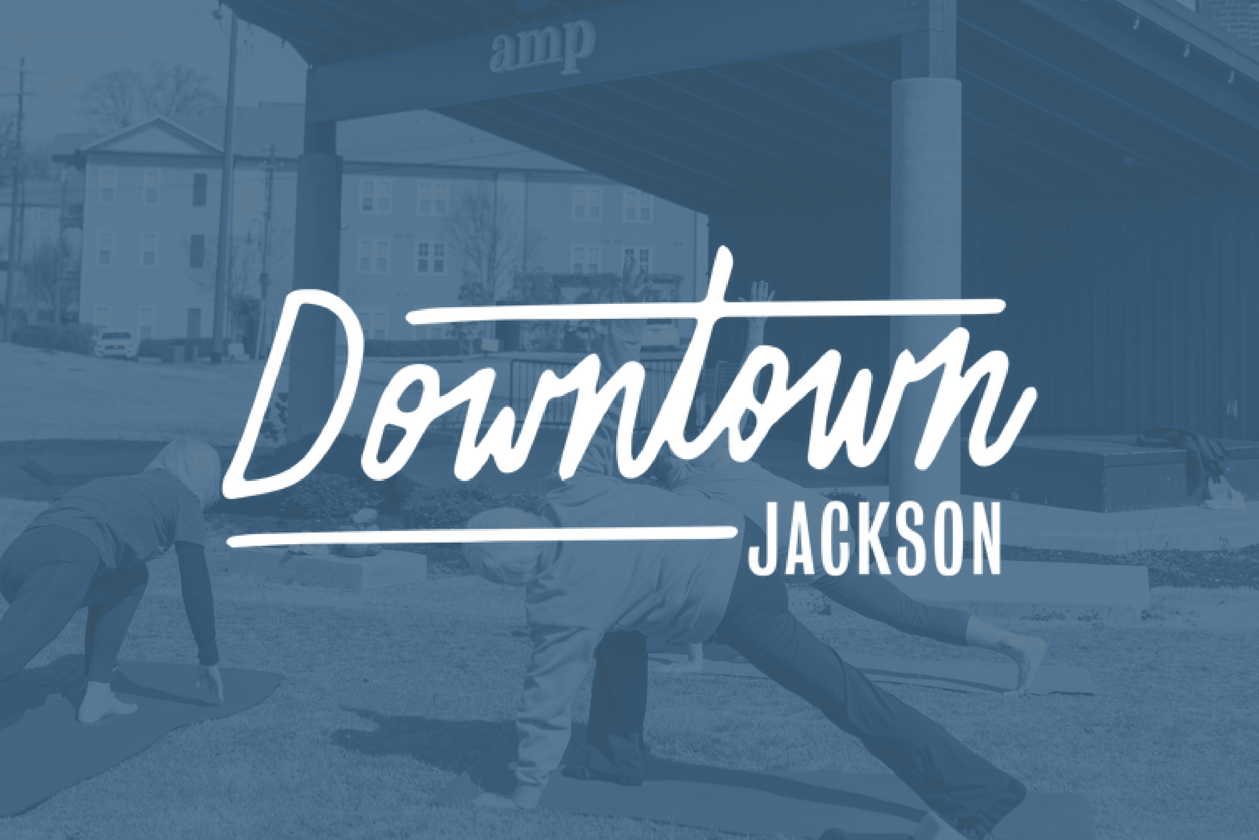 'Downtown Jackson' logo overlayed on a street scene with people doing yoga outdoors