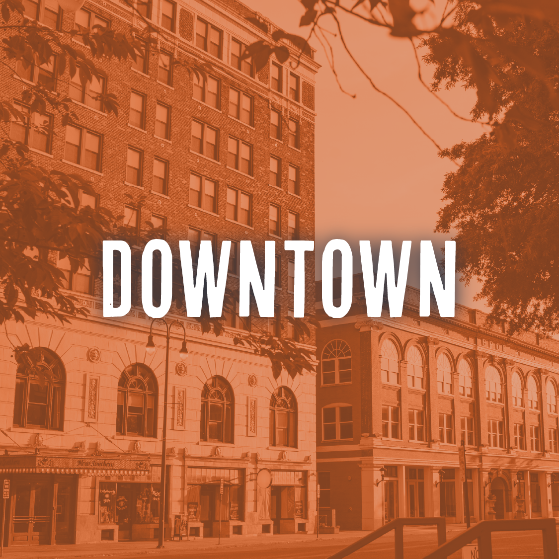 A city street with historic buildings, trees, and street lamps, with the word 'DOWNTOWN' overlayed in bold letters.