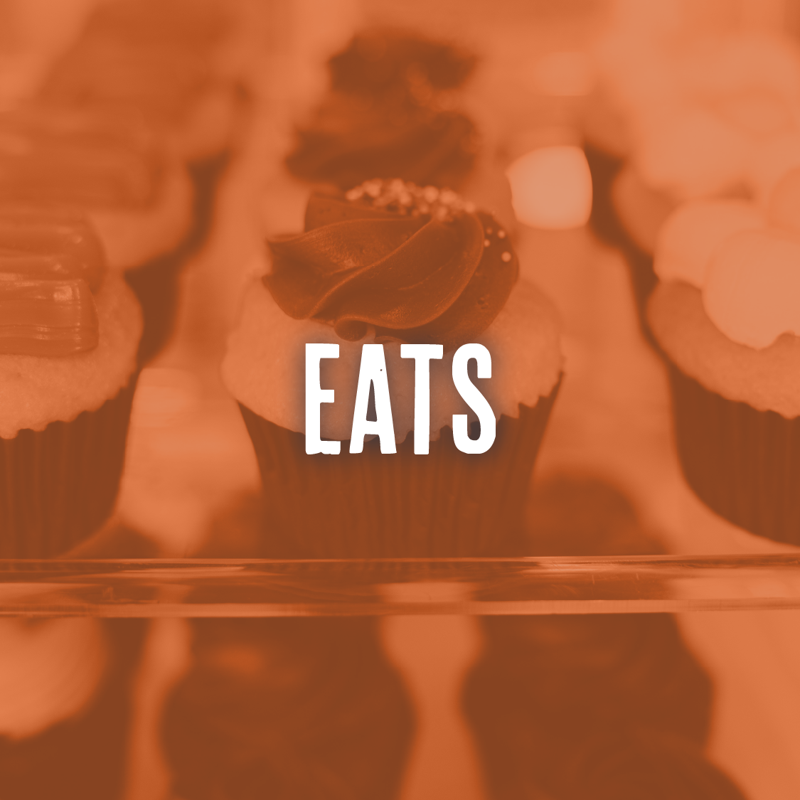 Close-up of cupcakes with frosting and toppings, with the word 'EATS' overlaid.