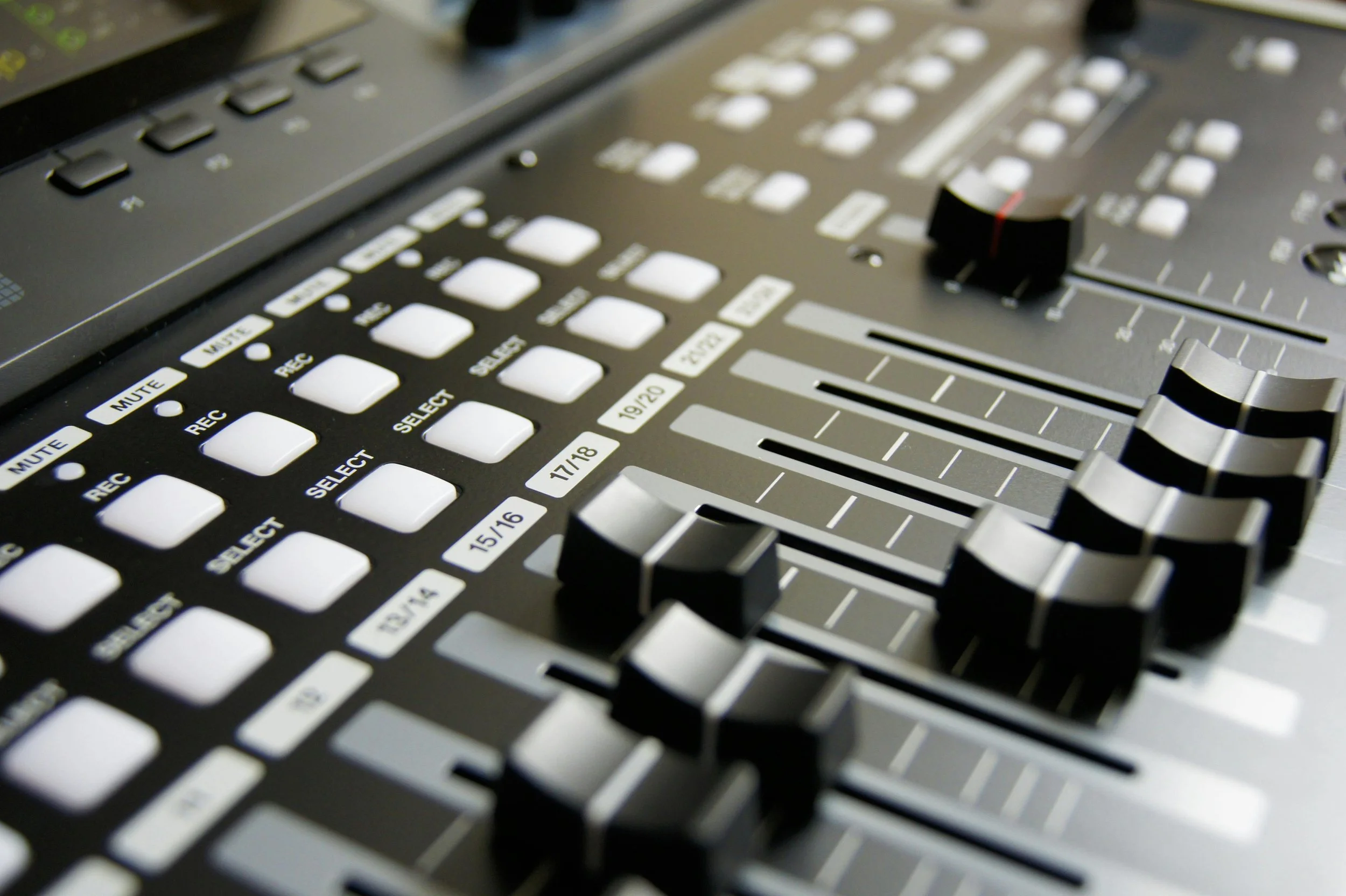 Pannello di controllo di un mixer audio con fader e pulsanti.