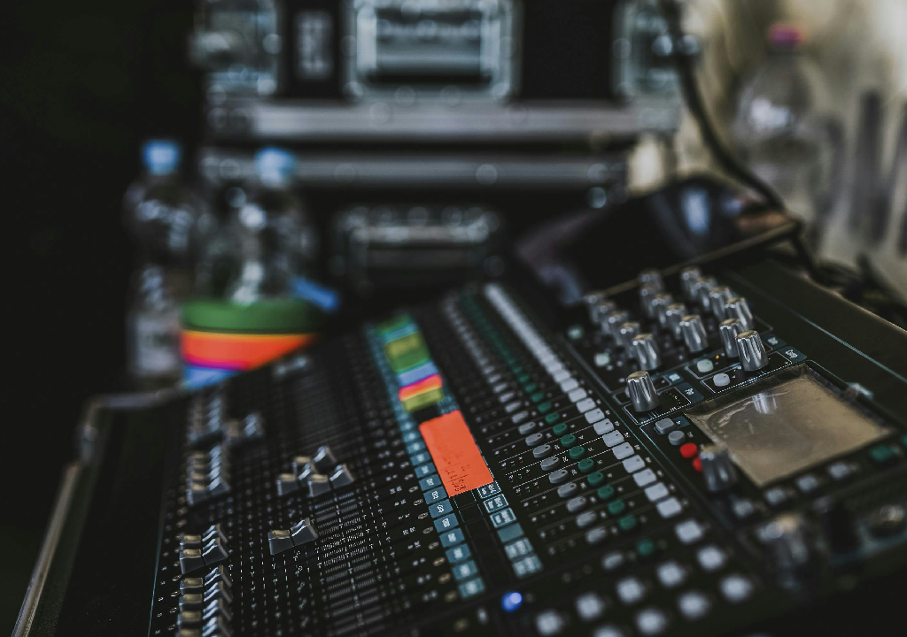 Mixer audio con manopole e fader, sfondo con bottiglie d'acqua