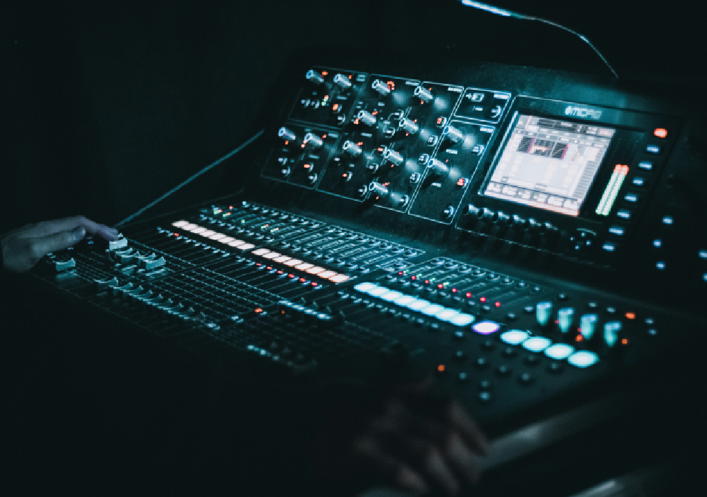Console di mixing digitale con molti pulsanti e display luminosi in un ambiente buio.
