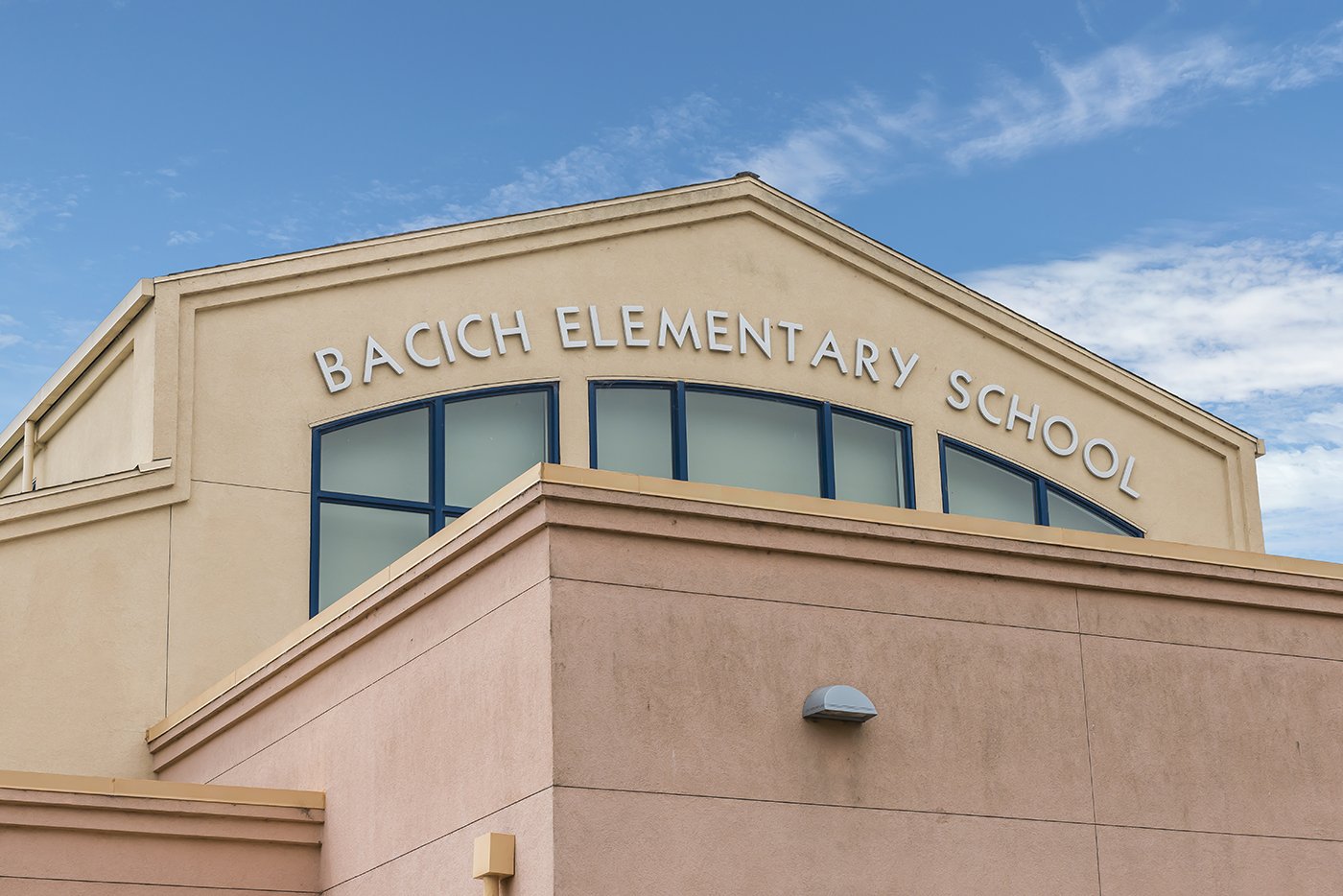 Exterior of Bacich Elementary School building with blue sky and clouds in the background.