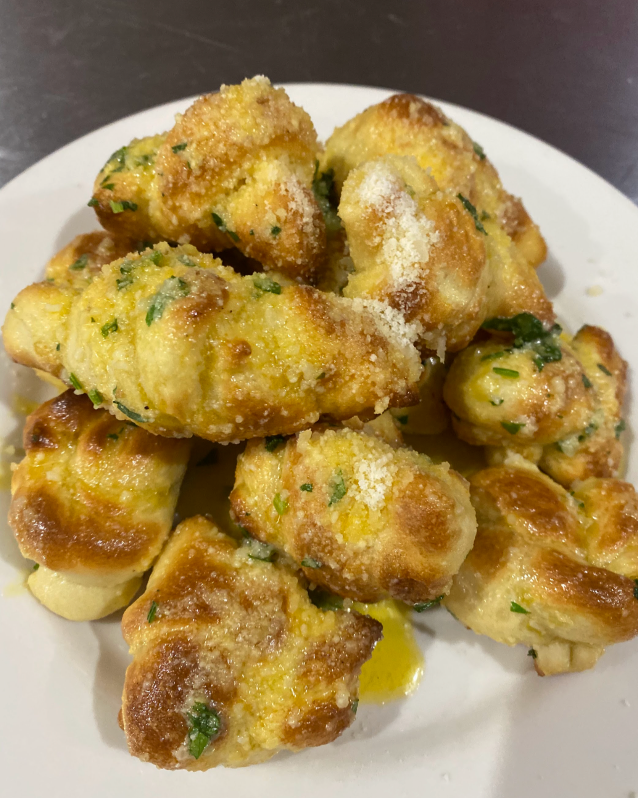 Plate of garlic Parmesan roasted cauliflower florets garnished with chopped parsley and sprinkled with grated Parmesan cheese.