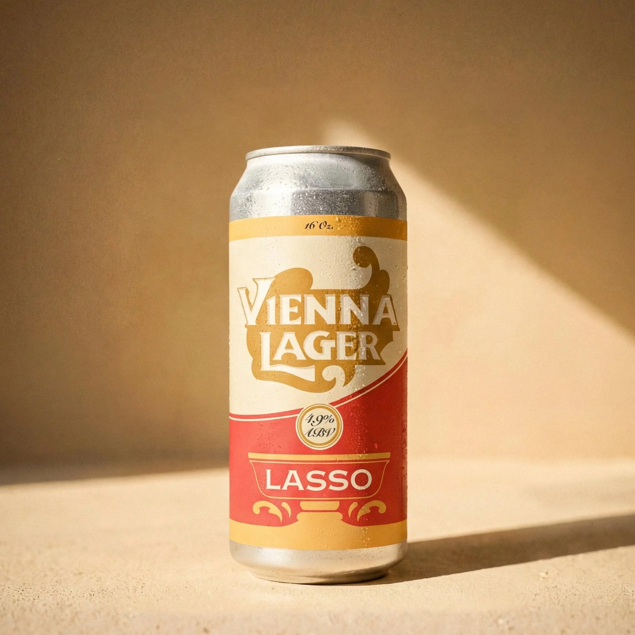 A can of Vienna Lager beer with a red and gold label, placed on a beige surface with sunlight casting shadows.