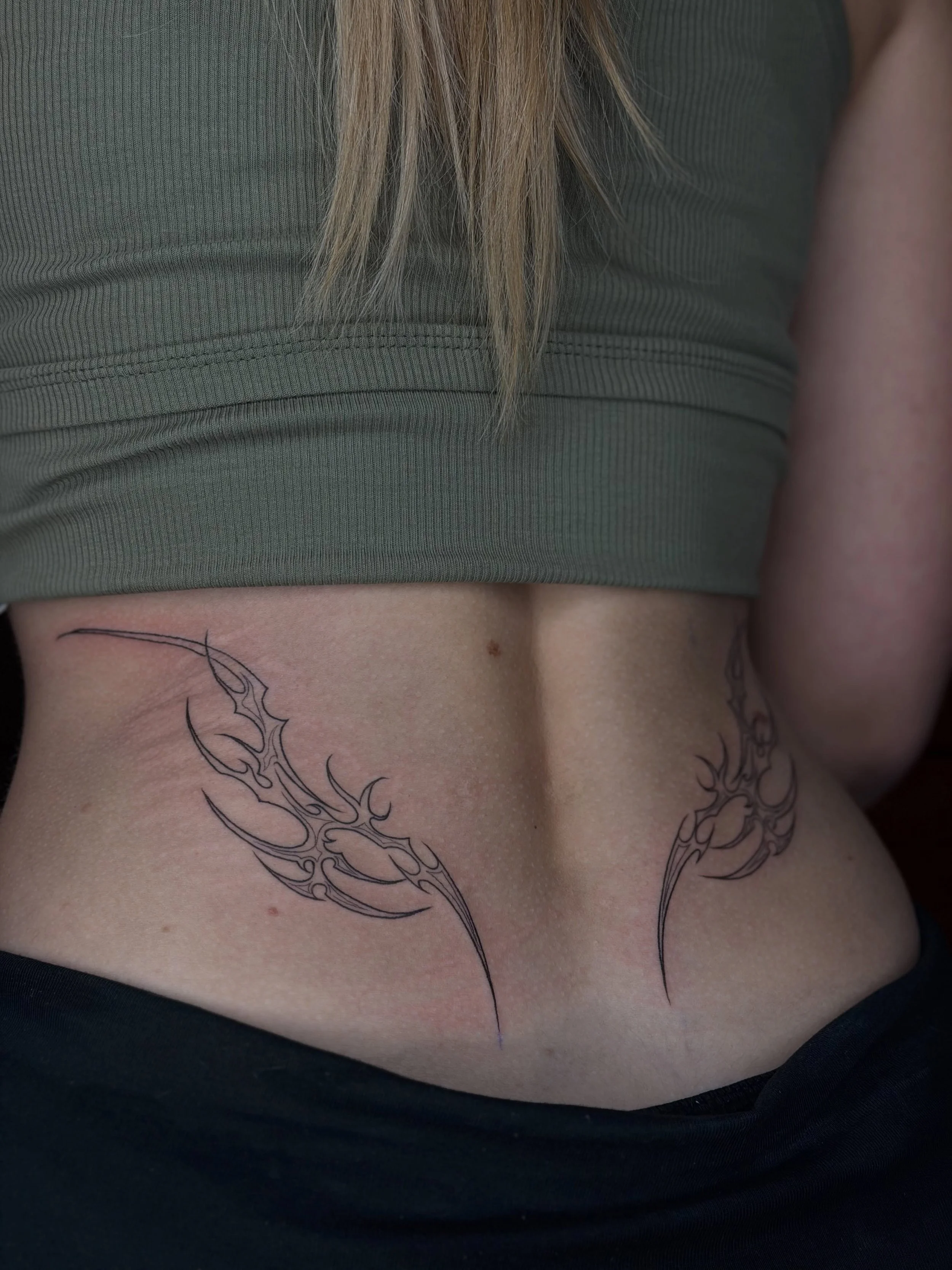 Two tribal tattoo pieces placed higher on the back &mdash; shaped to follow the waist and body flow naturally.

Strong lines, balanced movement, and a placement that contours the silhouette so beautifully.
I love how this design frames the body witho