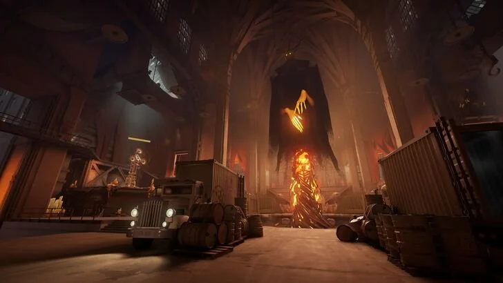 Inside a large, dark cathedral with a giant flaming apocalypse statue and a large banner hanging from the ceiling. There are trucks and barrels in the foreground, and the scene has a fiery, apocalyptic atmosphere.