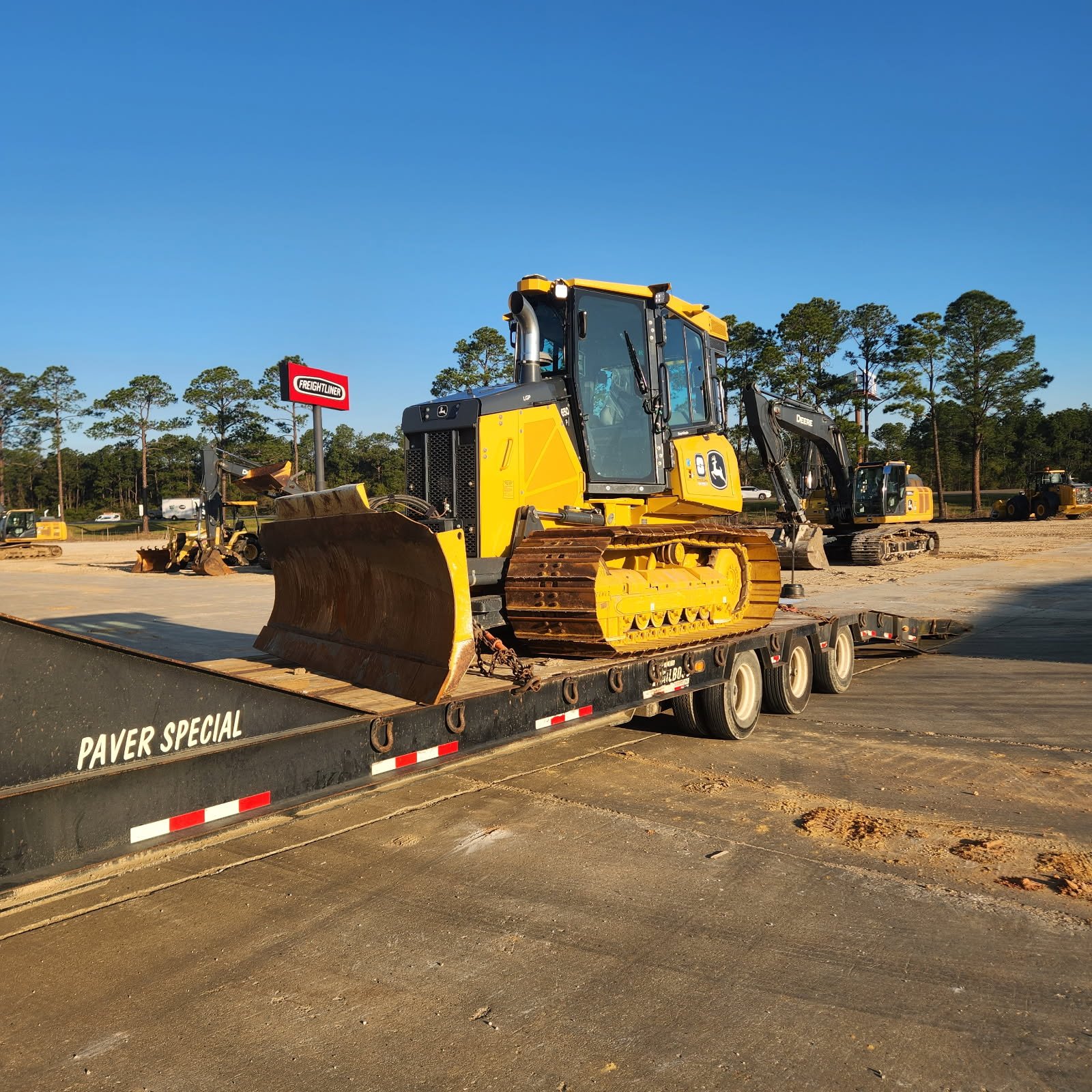 A yellow and black bulldozer on a flatbed trailer at a construction site.