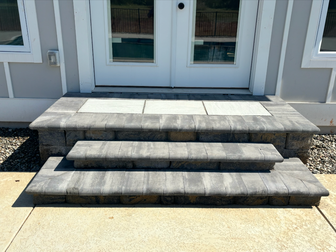 Stone steps leading to a glass door with a white frame.