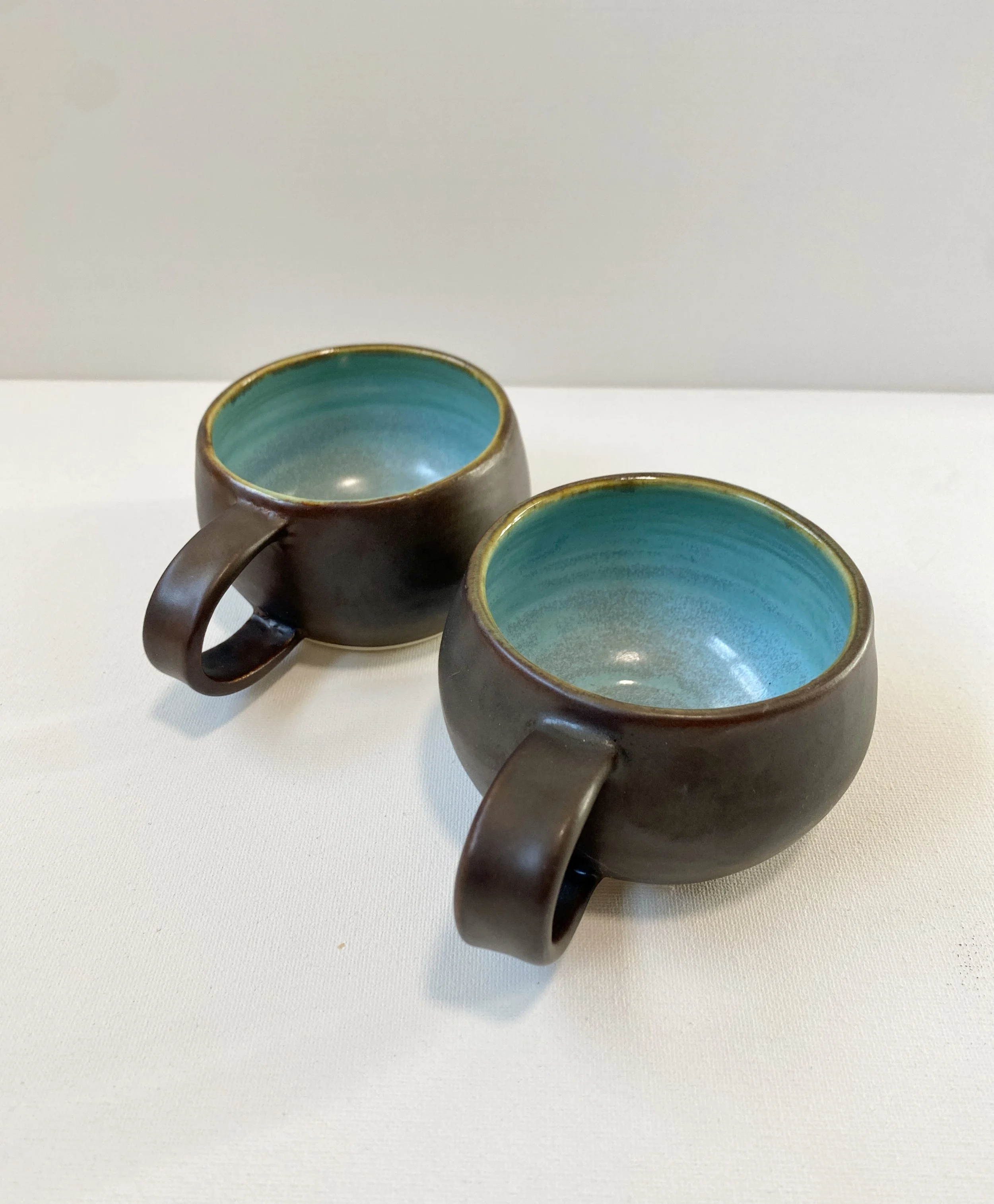 two brown metallic mugs with light blue interior