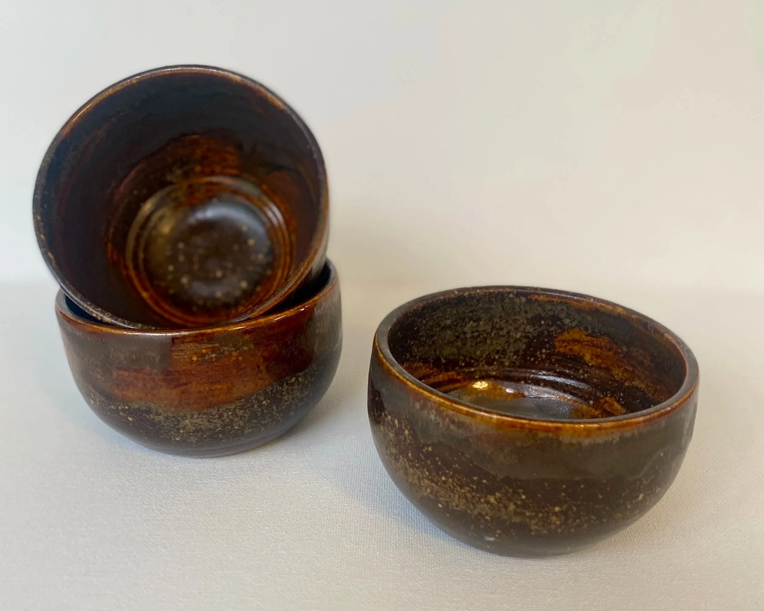 three small brown metallic snack bowls, two next to each other, one stacked on top