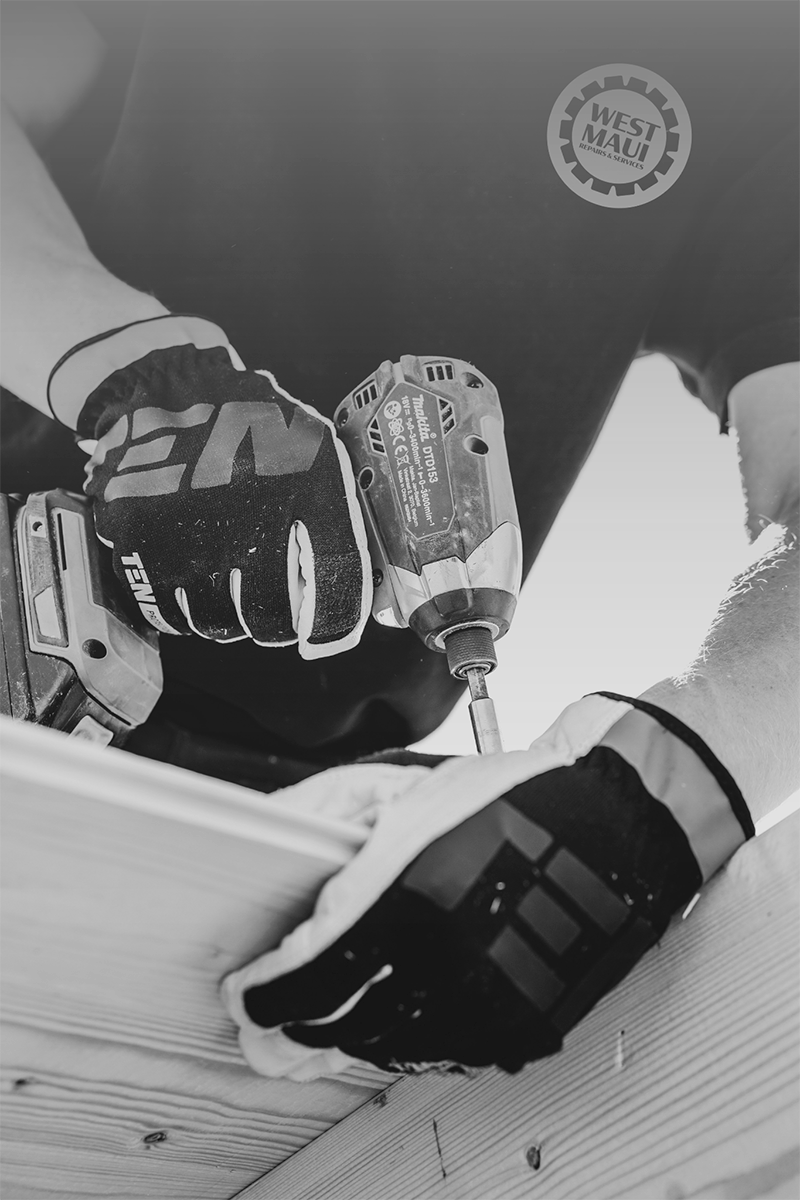 Person using a cordless drill to work on a wooden surface during construction or woodworking, wearing gloves.