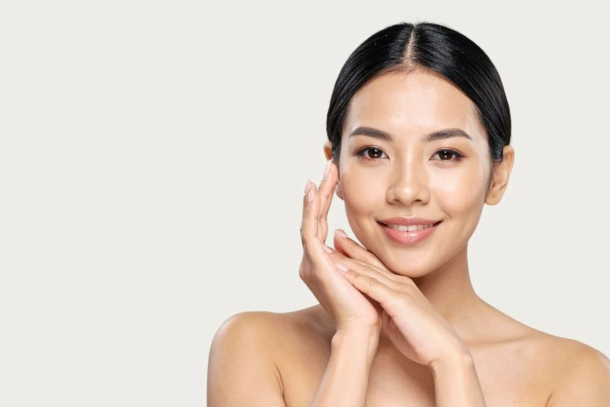 Woman touching her face with clear skin representing natural aesthetic results