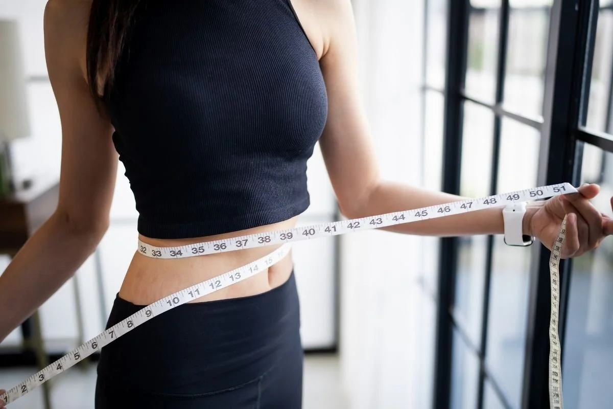 Woman measuring her waist to show weight loss from medical weight loss services at Medspa 501