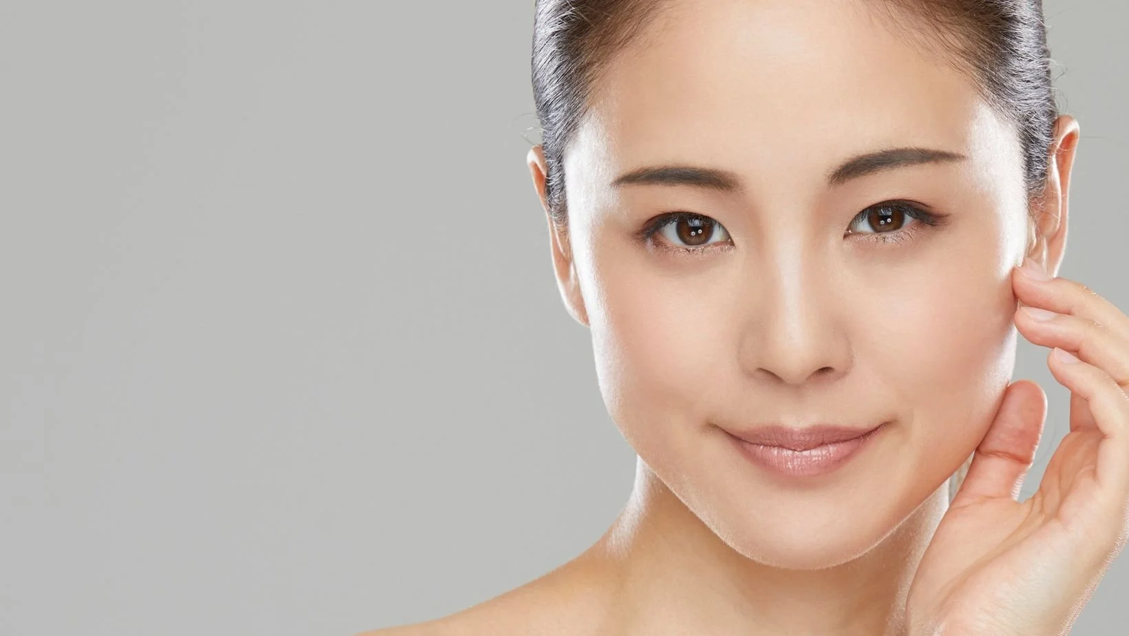 Woman touching her face with clear skin representing natural aesthetic results