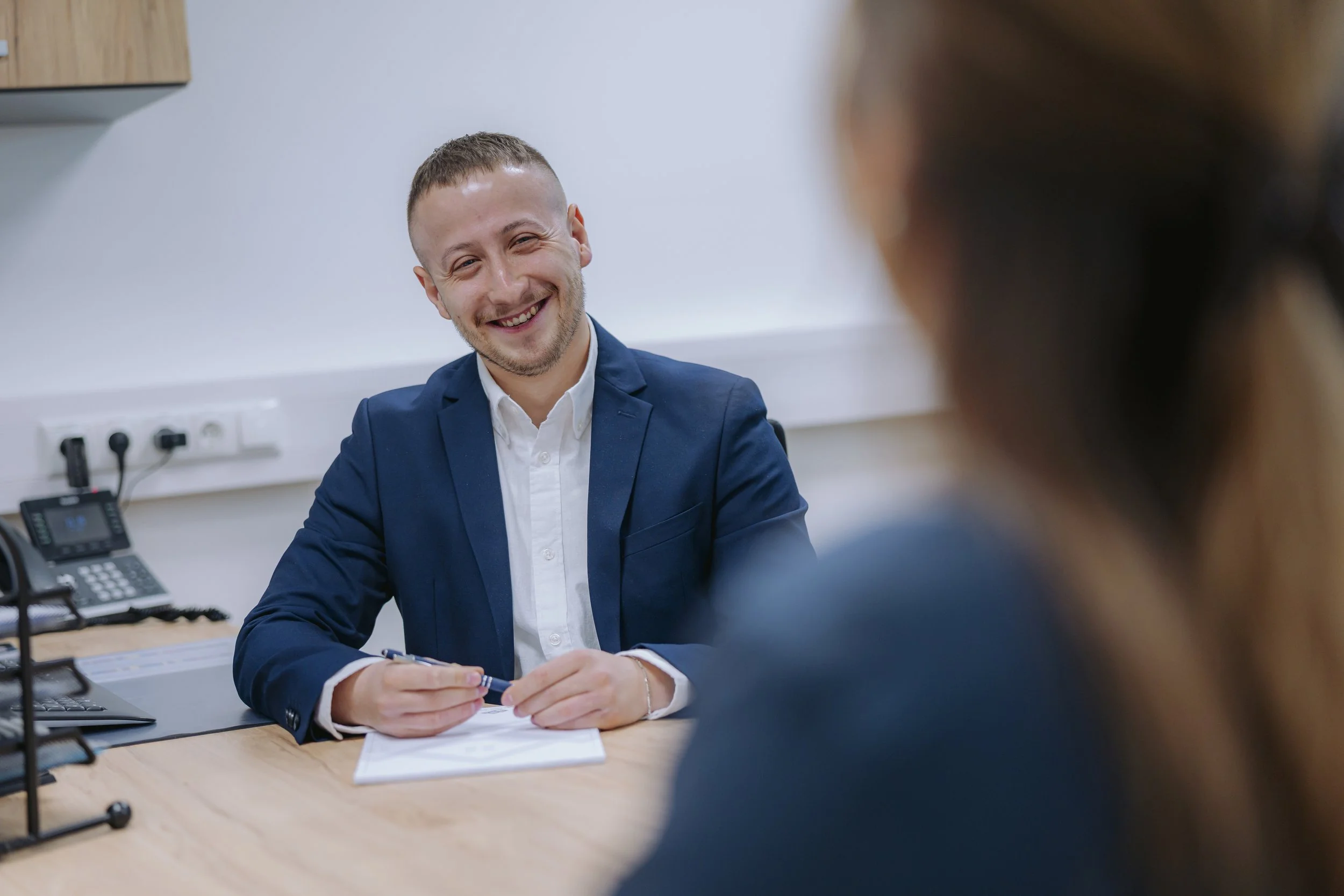Geschäftsmann im Büro redet mit einer Frau, lächelnd und zuversichtlich.