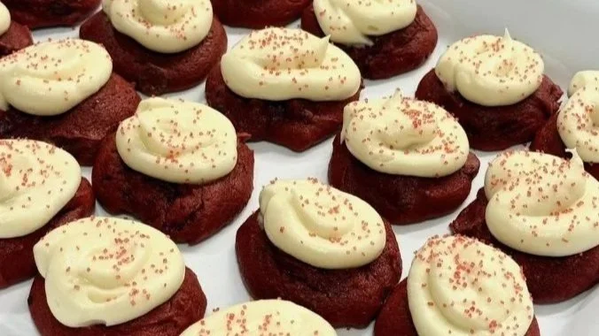 Red velvet cookies topped with cream cheese frosting and pink sprinkles