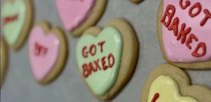 Decorated heart-shaped cookies with colorful icing and various messages written in red icing.