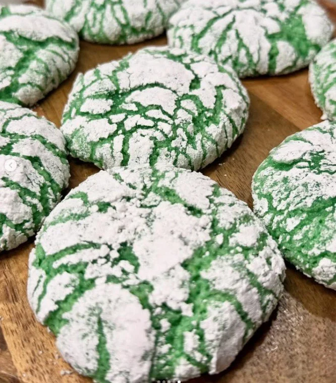 Green and white snowflake-shaped cookies on a wooden surface.