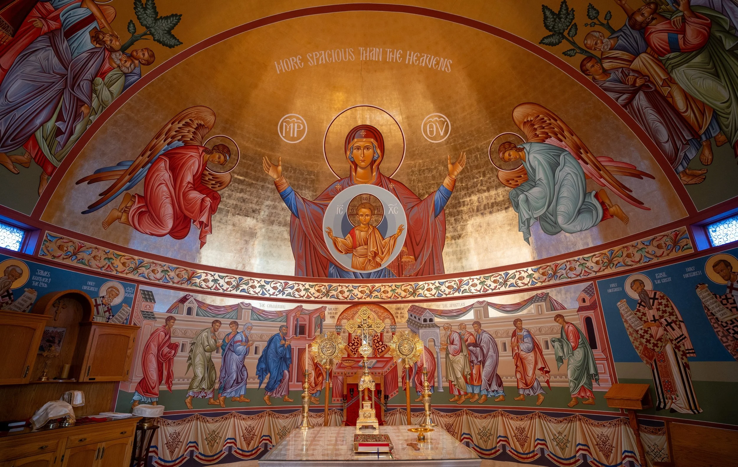 Saint George Orthodox Cathedral interior view of the altar with an elaborate gold-colored mural depicting religious figures, with an altar and religious artifacts in the foreground.