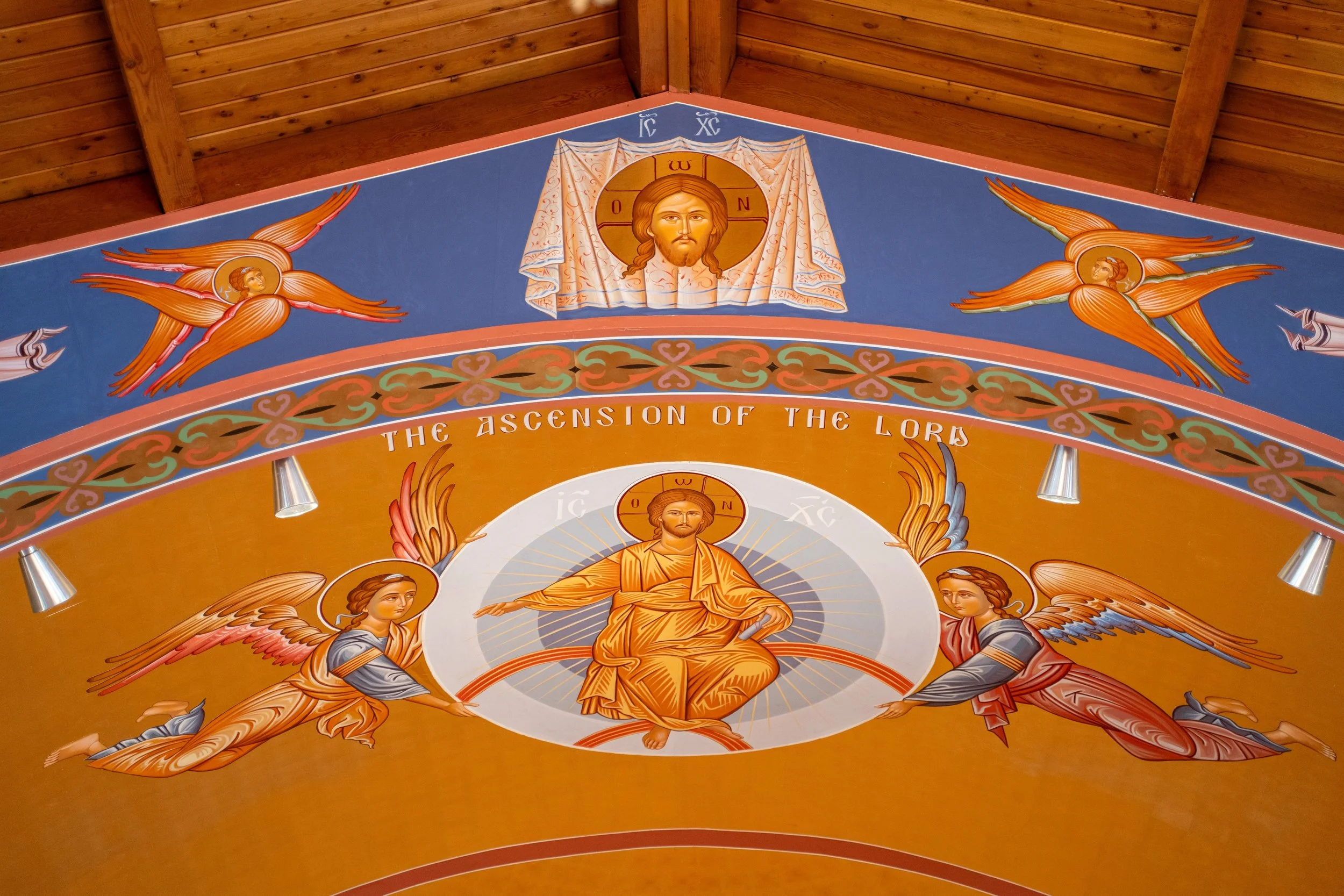 Religious artwork on a church ceiling featuring Jesus Christ with a halo, an inscription that says 'The Ascension of the Lord,' and angels with wings.