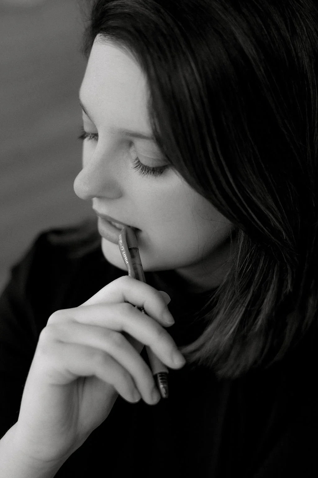 black and white photo of author holding pen to lips