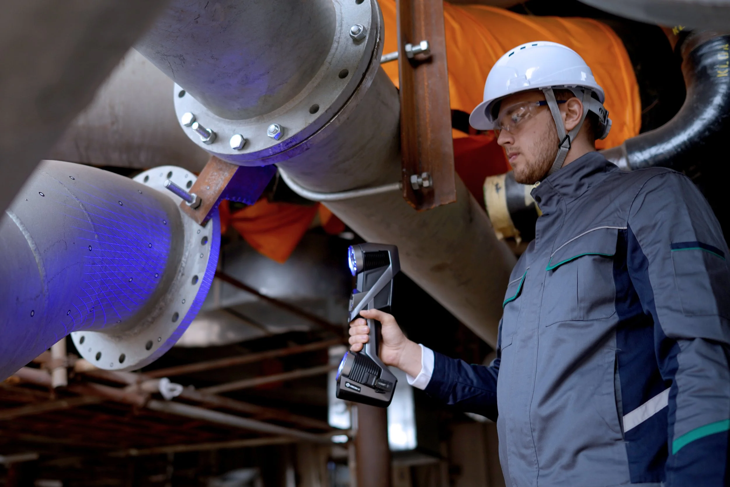 A technician scanning flanges with a handheld scanner in an industrial facility.