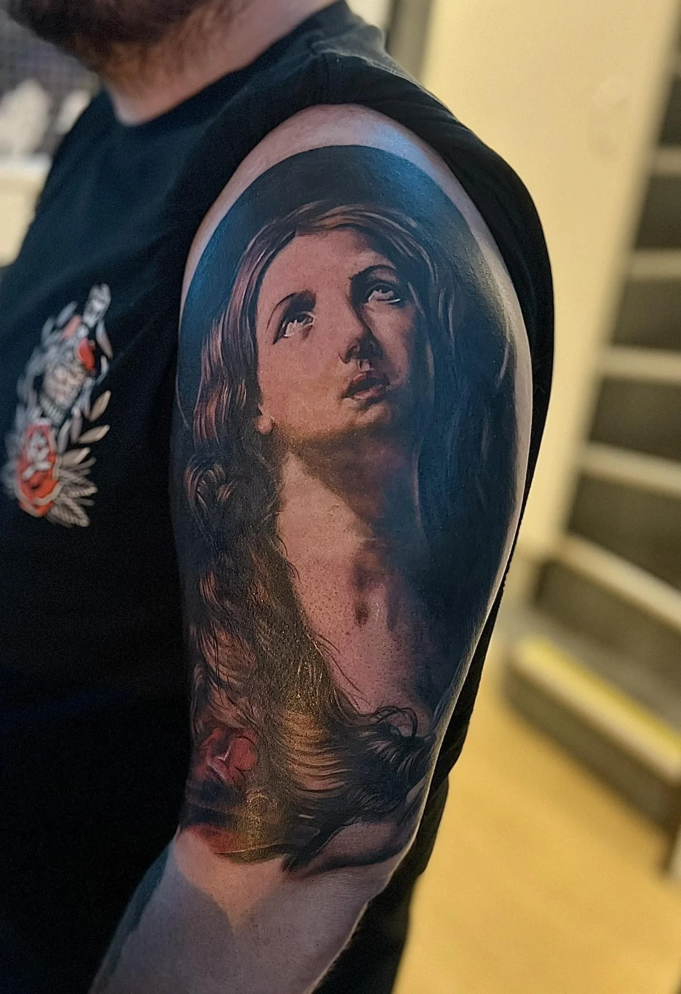 Tattoo of a woman's face with long flowing hair on a person's upper arm.