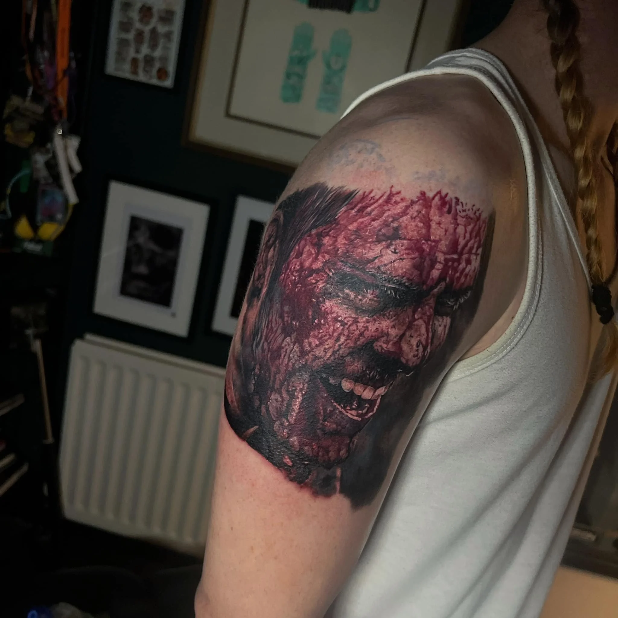 Close-up of a detailed tattoo of a zombie-like face on a person's upper arm, showing a ferocious expression, decayed skin, and horror-themed features.