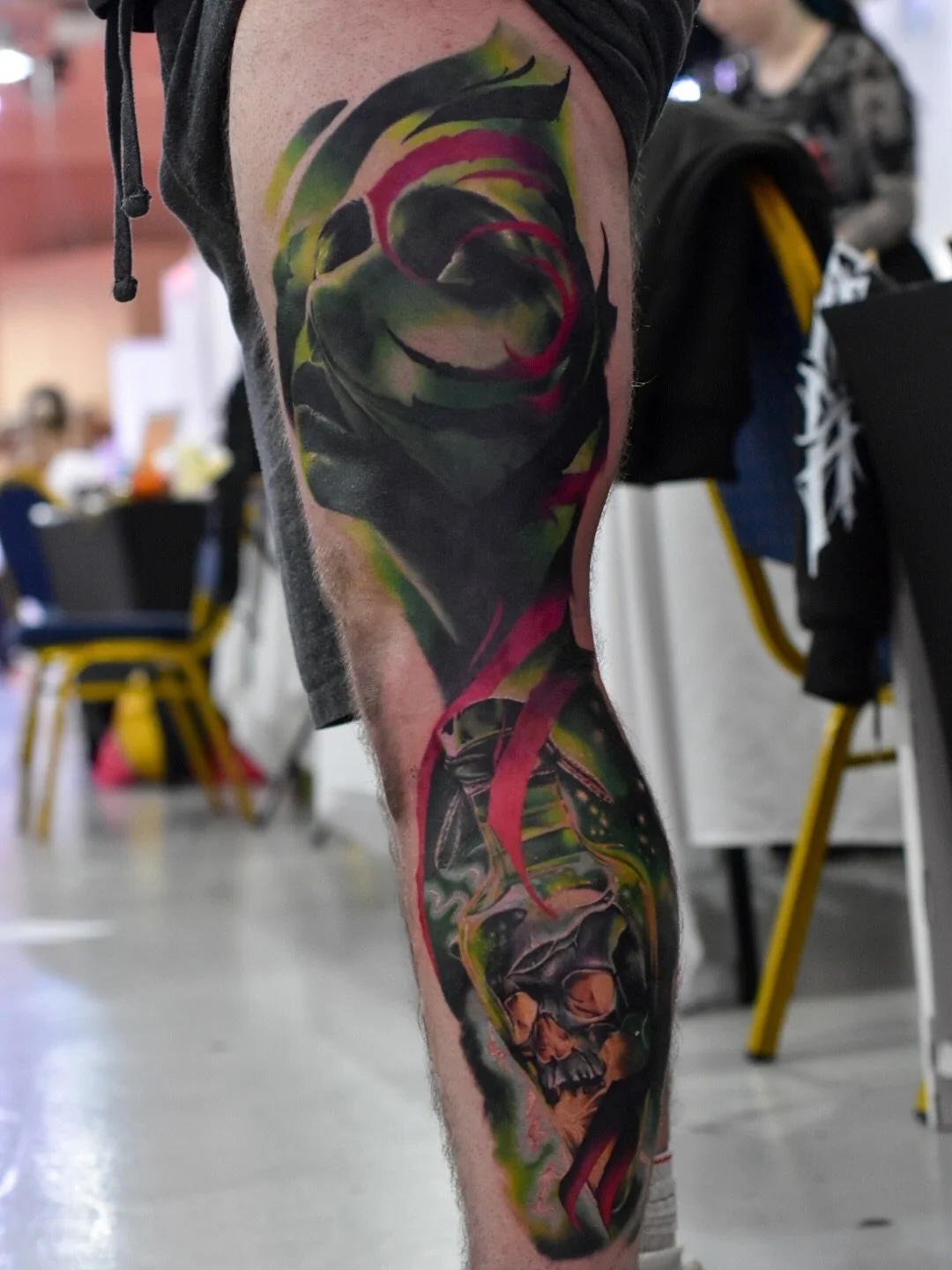 Colorful tattoo of a woman's face and a skull on a person's arm.